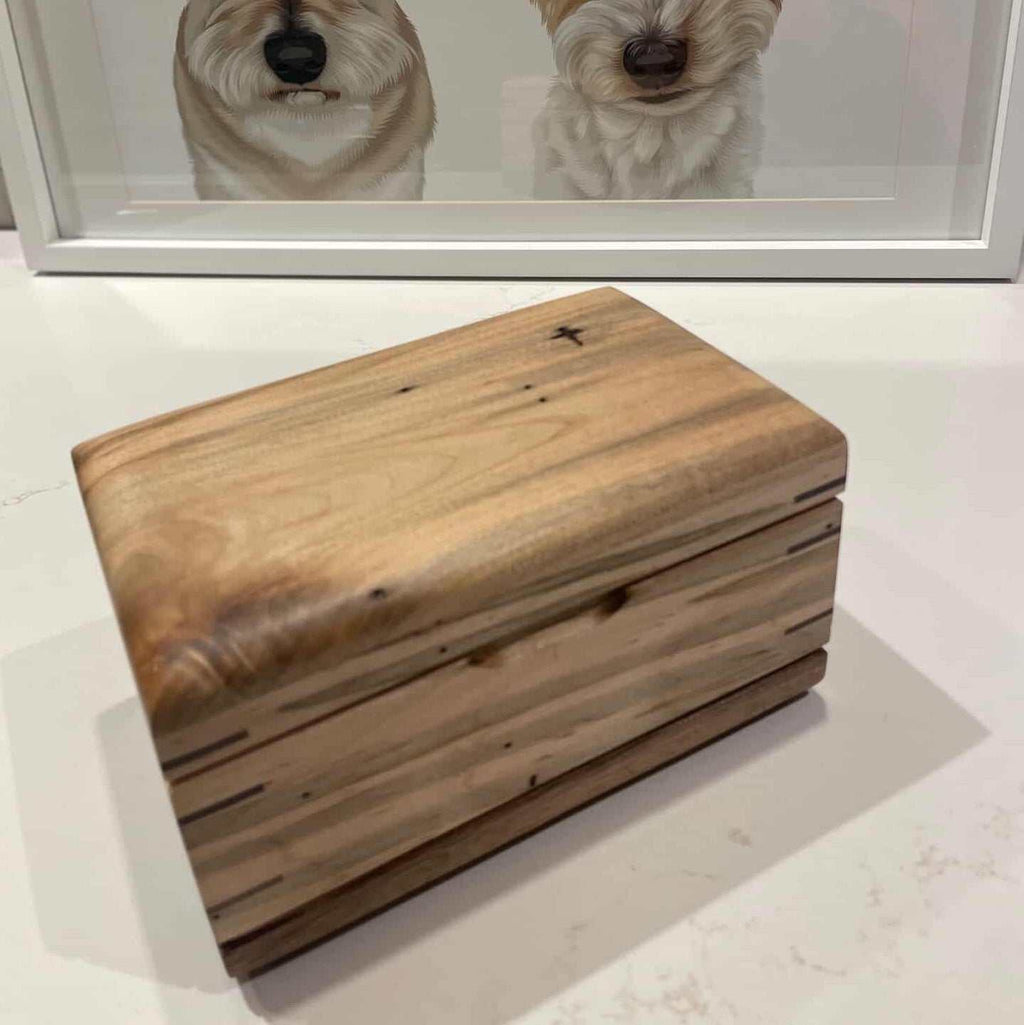 Handcrafted cremation urn for pets made from domestic hardwood with open paw design and custom engraving option